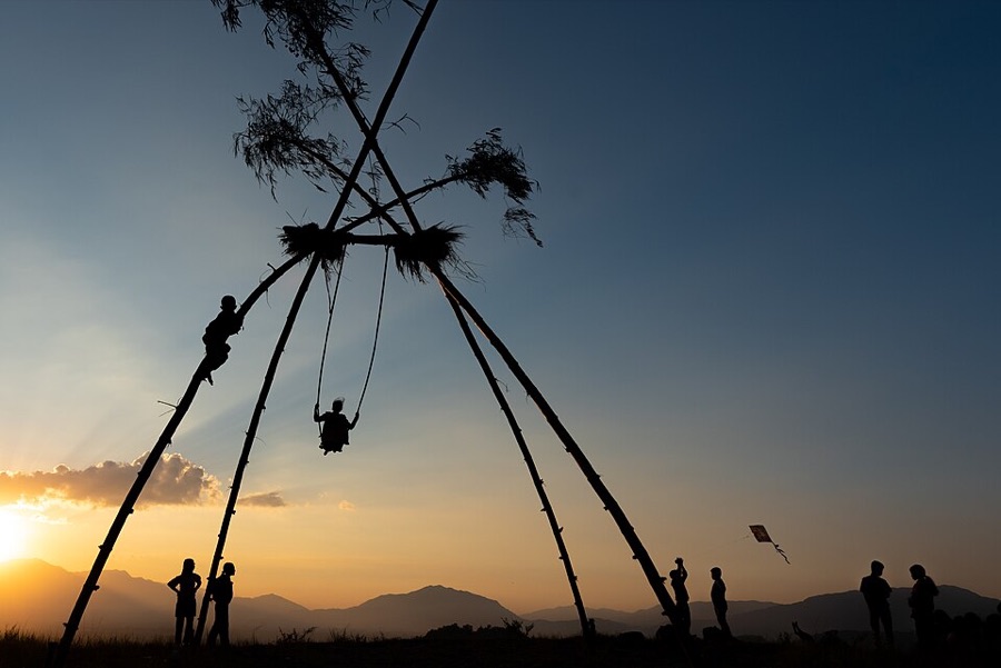 Silhouette of a tall bamboo Dashain swing against a sunset sky in Nepal