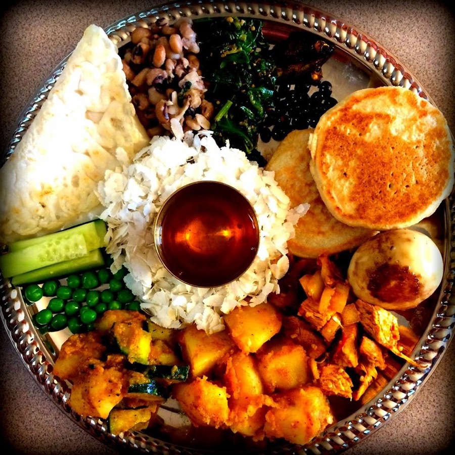A Newari Samay Baji platter with beaten rice, egg, woh lentil cakes, spiced potatoes, beans and greens around a small cup