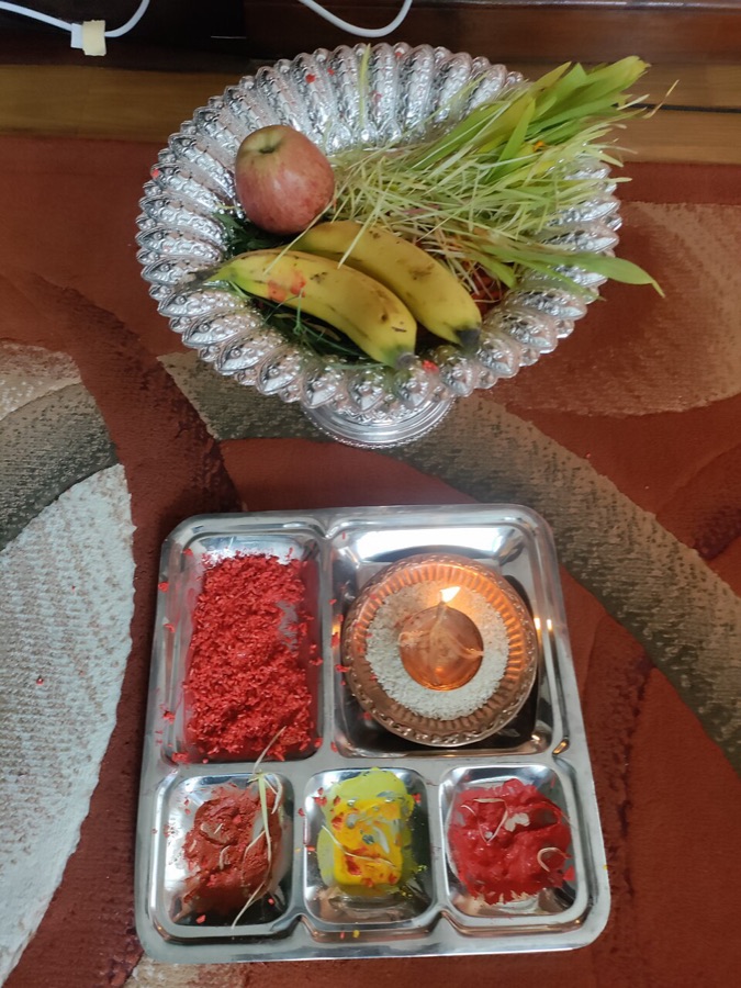 A plate of red tika, rice and sweets beside a bowl of jamara barley sprouts and fruit